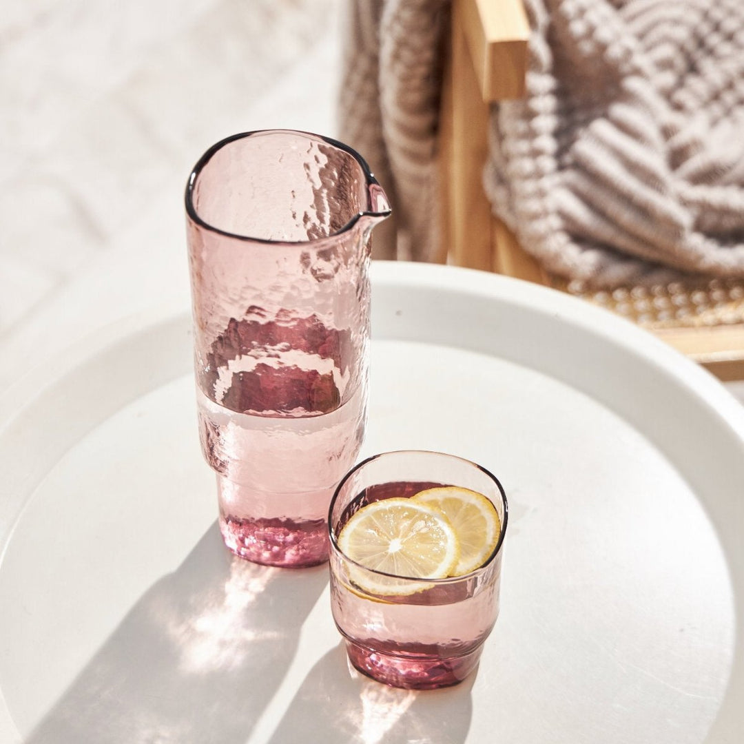 Set of pink handmade glass carafe and drinking glass with water