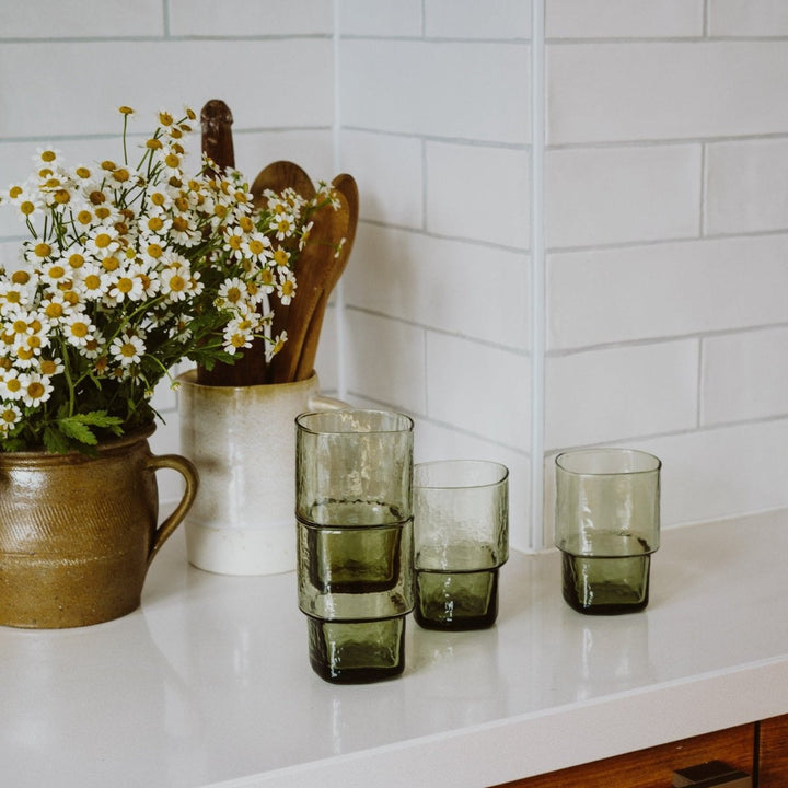 4 stackable, slim, angular olive-green handmade drinking glasses in a white kitchen