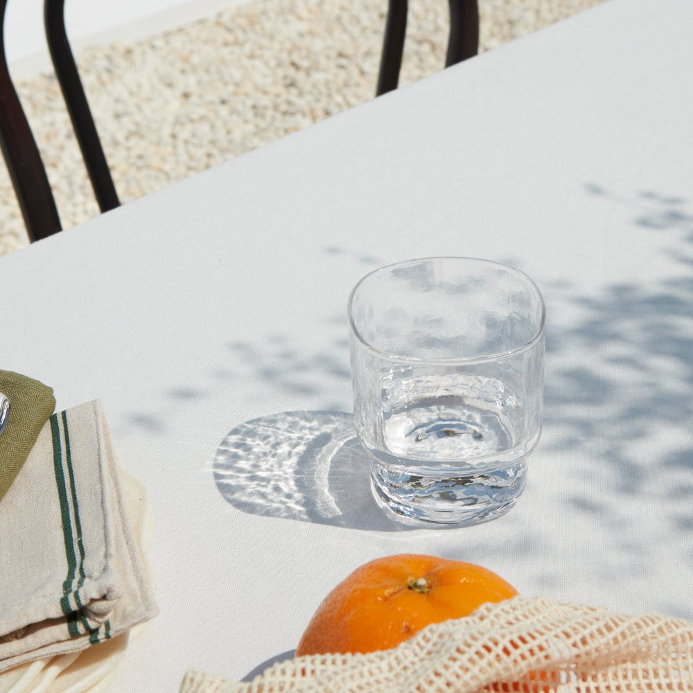 A stackable handmade clear drinking glass on a outdoor summer table