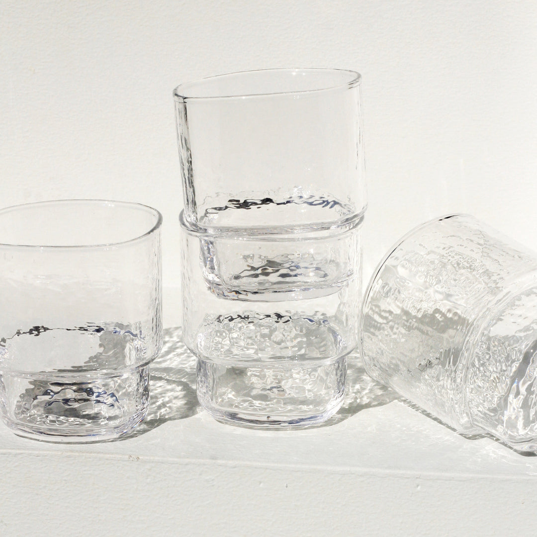 A modern, big, stackable handmade clear drinking glass in the sun