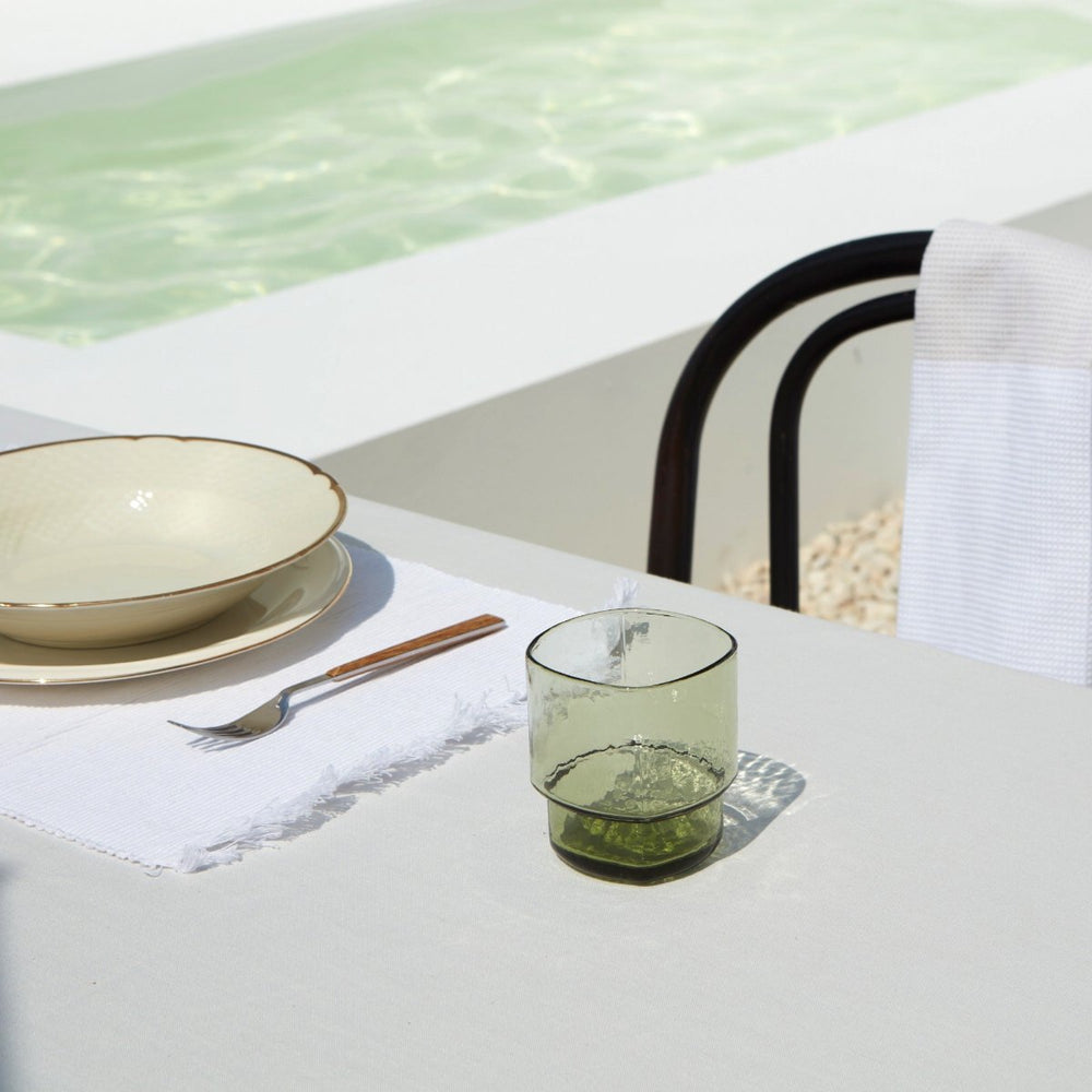 Big, stackable coloured handmade drinking glass in olive green in a green table setting