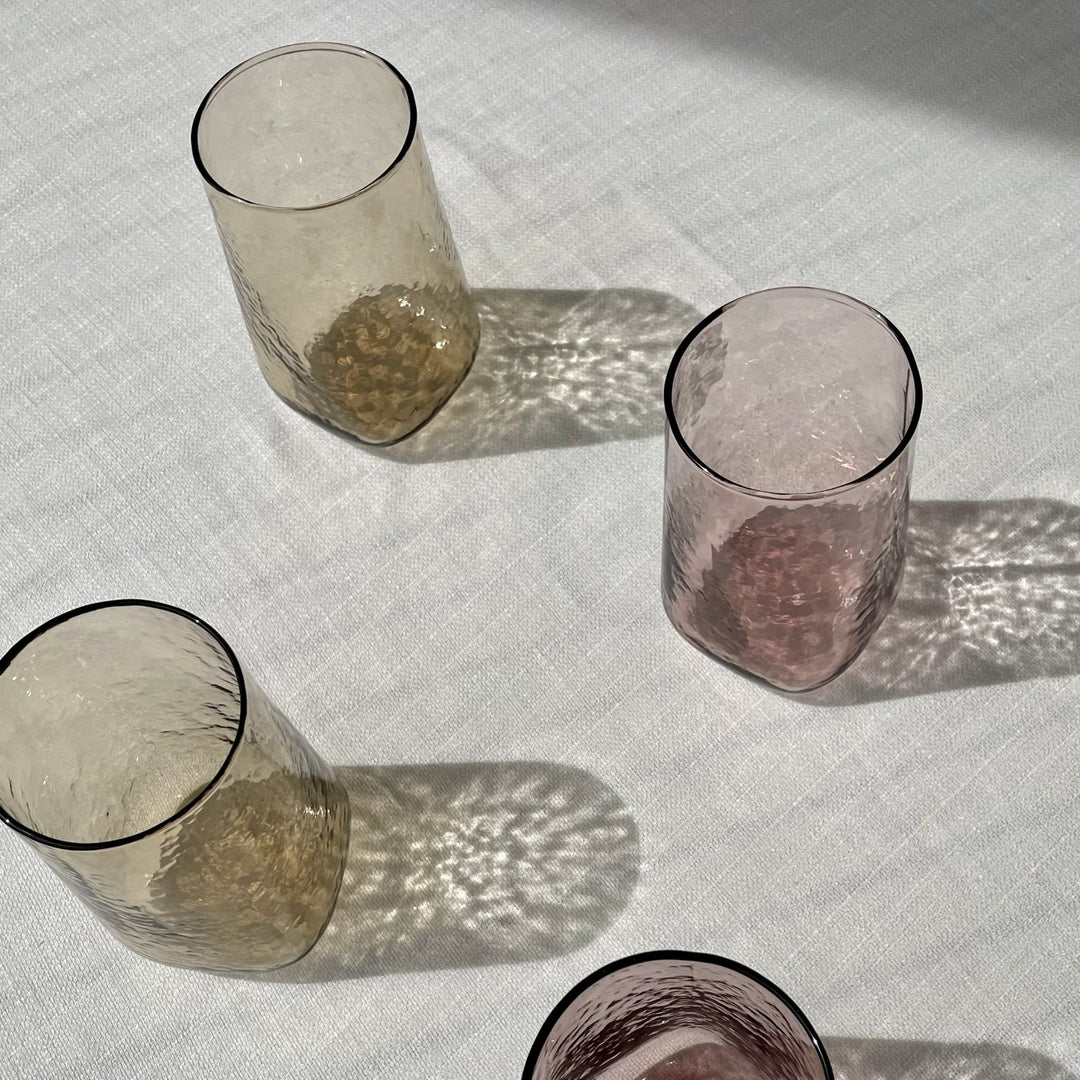 Brown and pink tall, unique drinking glasses with hammered texture in the sun