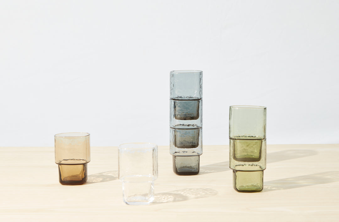Stackable handmade drinking glasses in brown, clear, smoke grey, and olive green