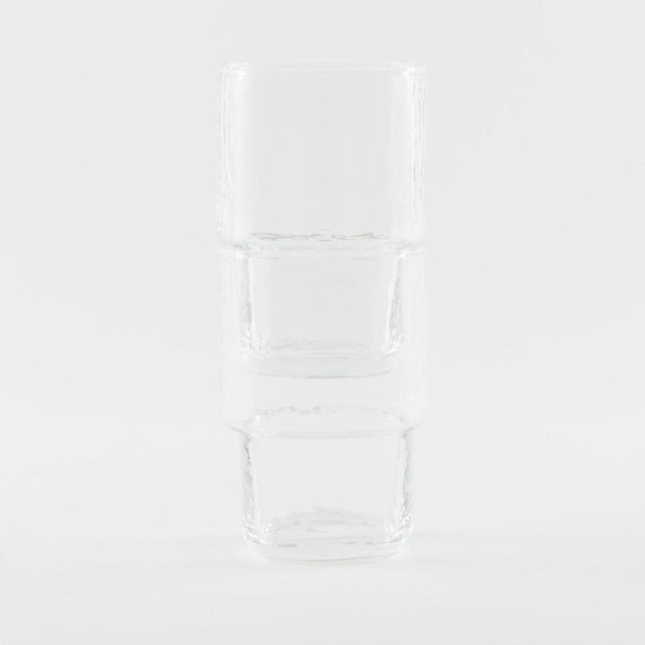 A set of 2 stackable, slim, clear handmade drinking glass with angular shape and hammered texture