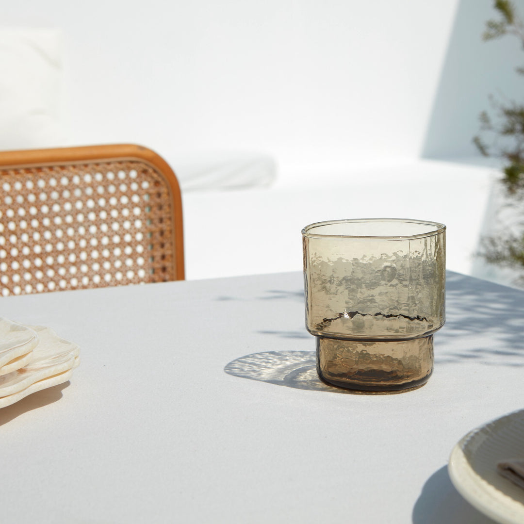A modern, big, stackable handmade brown drinking glasses on a summery table setting 