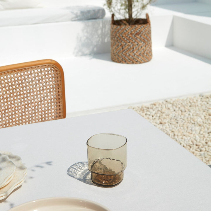 A big, stackable handmade brown drinking glasses on a summery table setting 