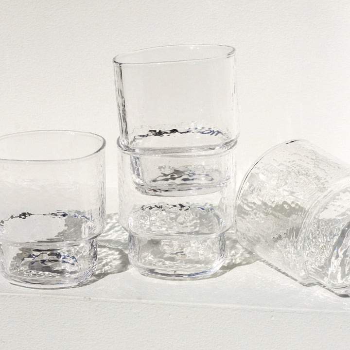 A modern, big, stackable handmade clear drinking glass in the sun