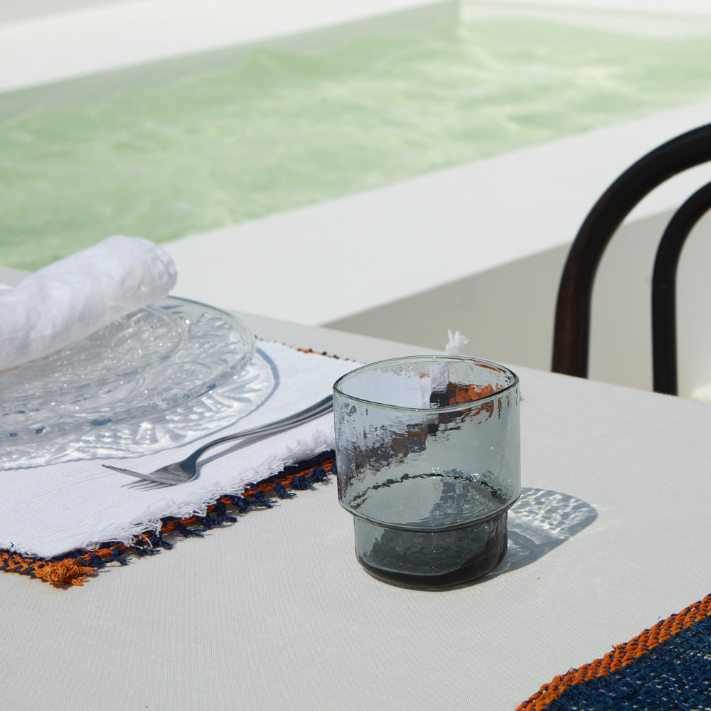 Modern, wide, big, stackable coloured handmade drinking glasses in blue grey on a summer table setting