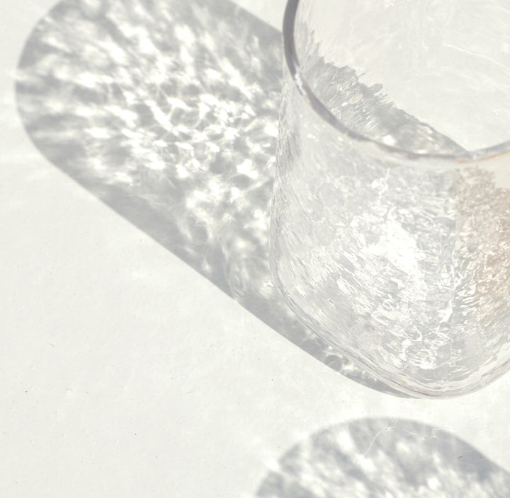 Bright sparkles of a clear drinking glass shadow