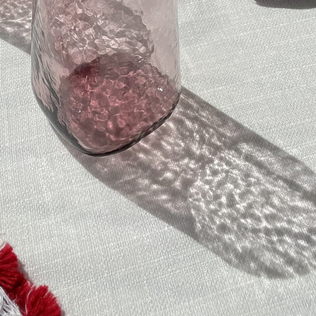 A close up of the hammered effect of a drinking glass in mulberry and its shadow