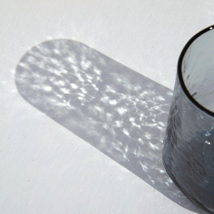 bright sparkly shadow of a blue glass with hammered effect