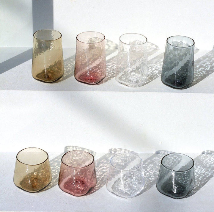 Big handmade coloured drinking glasses in brown, clear, pink and grey-blue 