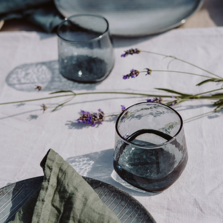 Blue-grey minimalistic drinking glass with a unique shape in an outdoor summer table setting